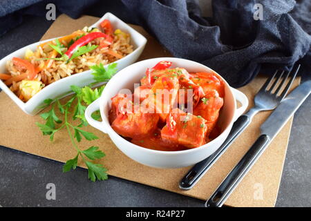 Hühnereintopf mit Ananas und Chili Tomatensauce in einer weißen Schüssel serviert mit gekochten Reis mit Gemüse. Gesunde Ernährung Konzept Stockfoto