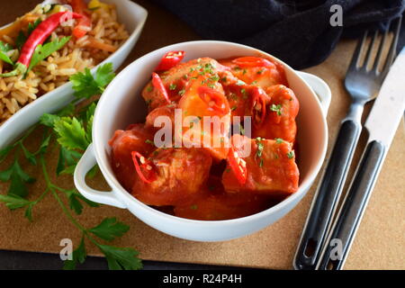 Hühnereintopf mit Ananas und Chili Tomatensauce in einer weißen Schüssel serviert mit gekochten Reis mit Gemüse. Gesunde Ernährung Konzept Stockfoto