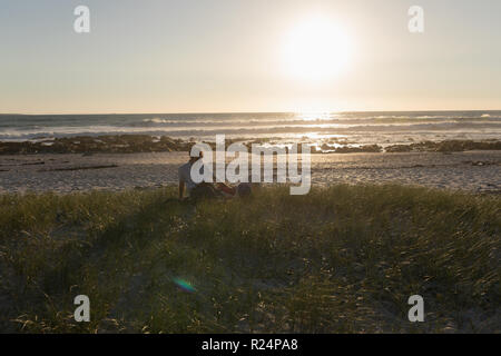 Liegende Frau auf mans Runde am Strand Stockfoto