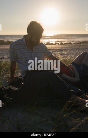 Liegende Frau auf mans Runde am Strand Stockfoto