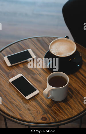 Tasse Kaffee und Handy am Tisch Stockfoto