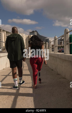 Paar halten sich an den Händen und laufen auf der Promenade Stockfoto