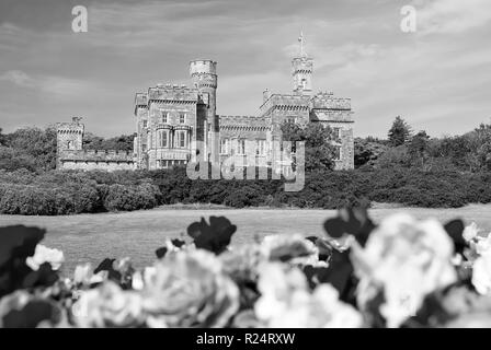 Lews Castle in Stornoway, Großbritannien mit unscharfen Rosen im Vordergrund. Schloss mit grüne Gelände am blauen Himmel. Historische Architektur und Design. Sehenswürdigkeiten und Attraktionen. Sommer Urlaub auf der Insel. Stockfoto