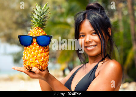 Schöne Frau im Bikini holding Ananas Obst am tropischen Strand Stockfoto