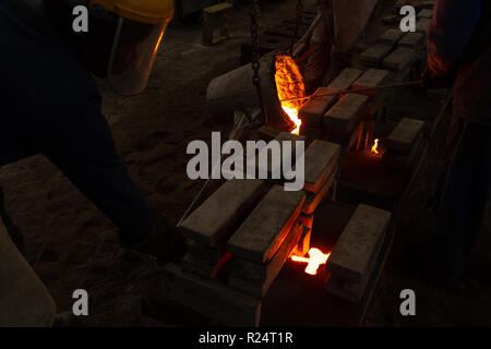 Arbeiter gießt geschmolzenes Metall von Flaschen in Formen Stockfoto