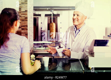 Latino Mann Koch in Uniform, Auftrag vom Kunden in fast food Restaurant Stockfoto