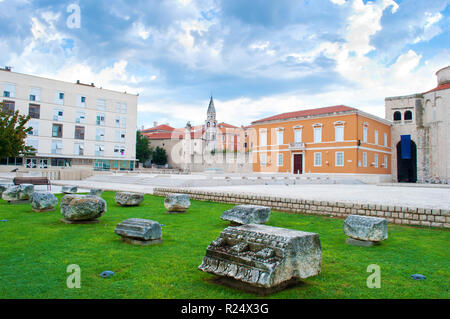 Leeren Platz Forum und steinerne Ruinen unter getrimmten Rasen an einem Sommermorgen. Dramatische Wolkenhimmel. Einsam und gemütlichen Zentrum von Zadar, Kroatien Stockfoto