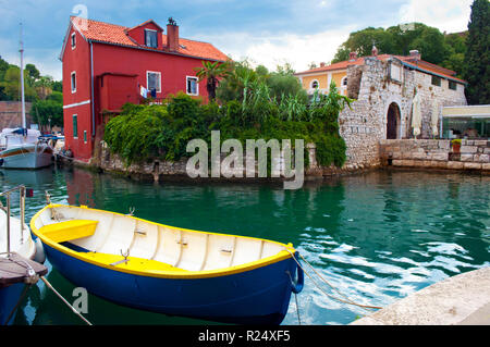 Gemütliche malerische Stadt Zadar, Kroatien. Rotes Haus unter grünen Efeu Laub in der Nähe von Emerald Wasser, wo eine blaue und gelbe Boot und mehrere Yachten sind Fl Stockfoto