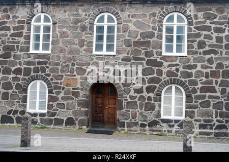 Alte steinerne Gebäude mit Windows. Wand, die aus großen Steinen. Alte Material Konzept. Alte steinerne Haus oder Teil der Verteidigungsanlagen. Gebäude mit dicken Wänden und schwere hölzerne Tür. Stockfoto