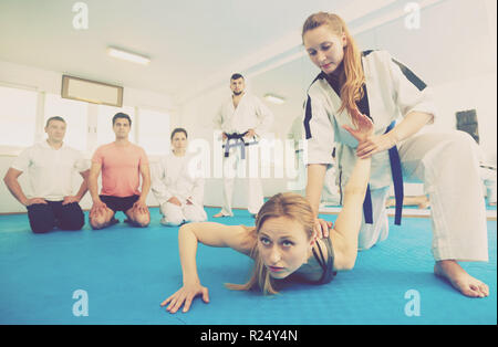 Junge weibliche Trainer zeigen schmerzhaft halten Sie für Erwachsene in Taekwondo Klasse Stockfoto