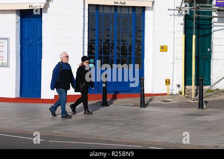 Hastings, East Sussex, Großbritannien. 17. November 2018. UK Wetter: Sonniger, aber kühler Wind in der Küstenstadt Hastings, wenn ein paar Leute entlang der Strandpromenade spazieren. Ein älteres Paar, das in hastings Hand in Hand geht. Foto-Kredit: Paul Lawrenson / Alamy Live Nachrichten Stockfoto