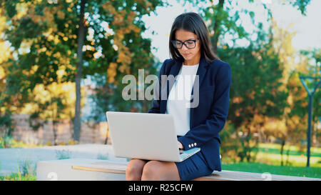 Erfolgreiche Geschäftsfrau mit Laptop auf Green Park Hintergrund. Schöne Mädchen in formale Abnutzung und Gläser im Internet surfen oder Arbeiten an Elec Stockfoto