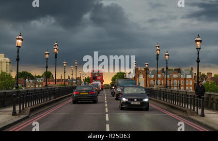 London, England, UK - 13. Mai 2014: Verkehr kreuze Battersea Bridge in West London unter Gewitterwolken und Sonnenuntergang Farben. Stockfoto