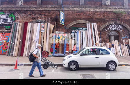 Fußgänger vorbei Teppiche für Verkauf an Sclater Straße Fleat Markt im East End von London. Stockfoto