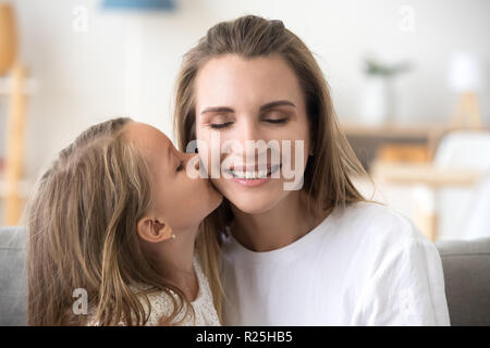Süßes kleines Kind Tochter glücklich lächelnde Mutter Küssen auf die Wange Stockfoto