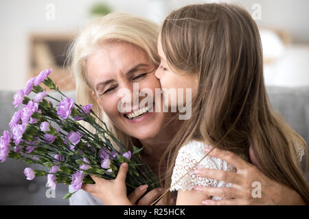 Kleine Enkelin küssen, blumen blumenstrauss congratulati Stockfoto