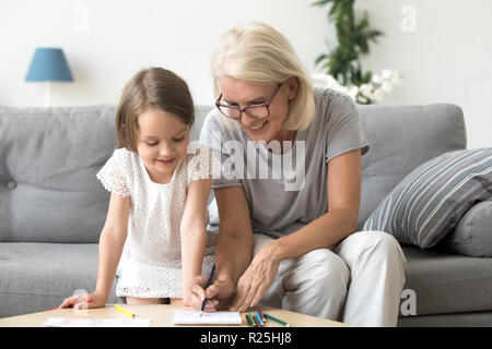 Lächelnde Großmutter und Enkelin zeichnen mit Farbe Stockfoto