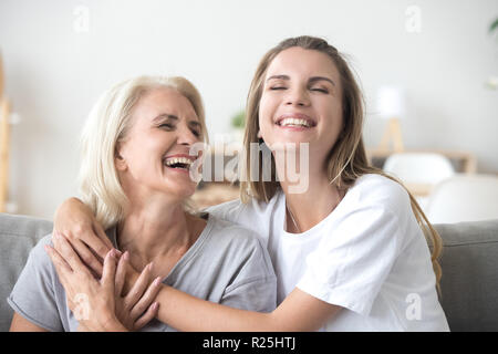 Happy senior reife Mutter umarmt jungen erwachsenen Frau lachend Stockfoto