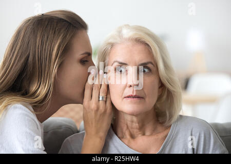 Ältere Frau hören jungen Freund whispering Geheimnis Schockiert Stockfoto