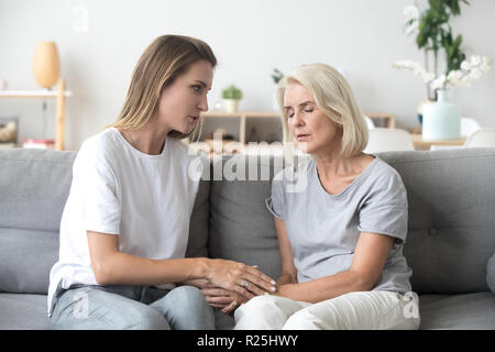 Erwachsene Tochter im Gespräch mit traurigen alten Mutter Unterstützung umgekippt Frau Stockfoto