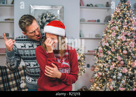 Sehr zornigen jungen Mann steht hinter Frau und nach oben zeigt. Er spricht zu ihr. Sie hält eine Hand auf Gesicht und schrie. Modell ist emotional Stockfoto