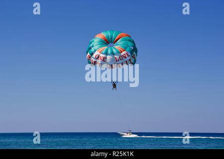 Parasailing an einem wolkenlosen Himmel mit einem grünen Fallschirm, in Negril, Jamaika Stockfoto