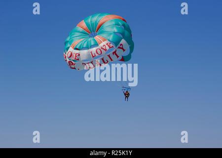 Parasailing an einem wolkenlosen Himmel mit einem grünen Fallschirm, in Negril, Jamaika Stockfoto