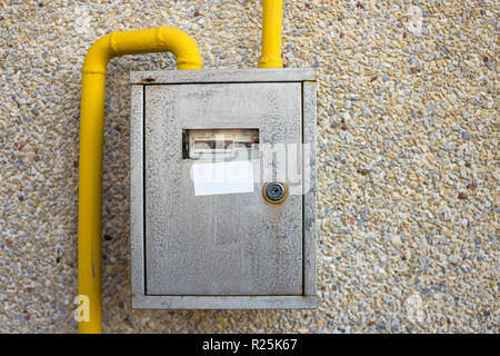 In der Nähe von Metall Stahl Gaszähler Box mit Anschluss gelben Leitungen hängen auf Exterieur Licht Haus aus Stein Wand. Bau, Renovierung, Messung t Stockfoto