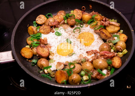 Pfanne mit Bratkartoffeln und Spiegeleier, Kartoffeln mit Kartoffeln, mit Frühlingszwiebeln, Stockfoto