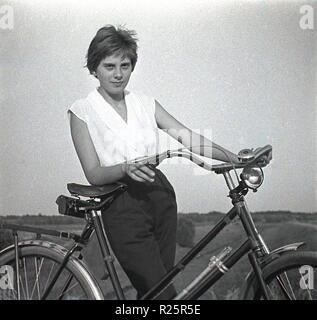 1960 s, attraktive junge Frau mit ihrem Fahrrad auf den Weg in die Landschaft. Stockfoto