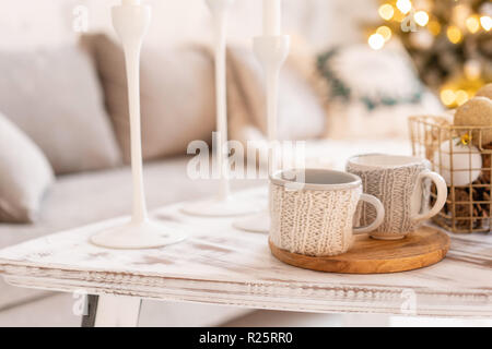 Gestrickte wollene Cups auf einen hölzernen Tisch. Zwei Tassen heißen Kaffee. Das Konzept der Wärme. Feiertage und Veranstaltungen. Herbst und Winter, Freizeit Konzept. Gemütliche, komfortabel, weich. Stockfoto