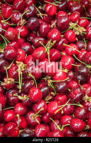 fresh red cherries with stalks on a market stall selling fresh colourful fruits. Stockfoto