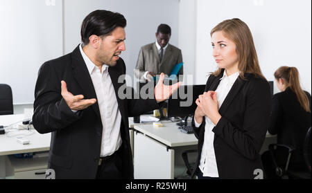Zornigen Mann Chef pointinting zu vermisst in der Arbeit zu weiblicher Manager arbeiten im Büro Stockfoto