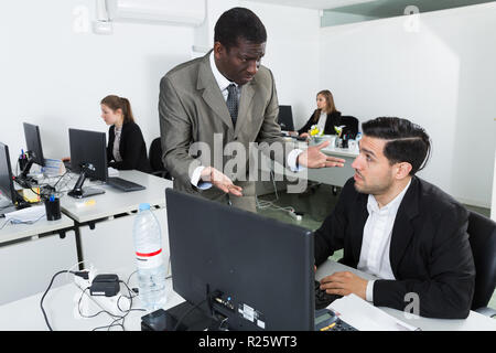 Man Manager arbeiten bei Laptop und verärgerten männlichen Chef pointinting zu vermisst in Arbeit Stockfoto