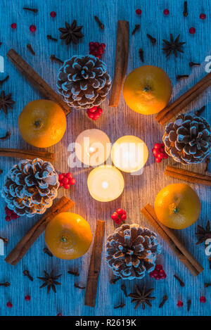 Weihnachten flach leuchtende Kerzen Kranz von kiefernzapfen, Orangen umgeben, Zimtstangen, Sternanis, Nelken, Beeren Stockfoto