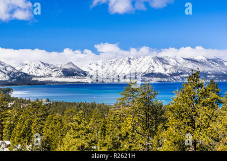 Blick auf Lake Tahoe auf einem sonnigen klaren Tag; die schneebedeckte Sierra Berge im Hintergrund; immergrüne Wälder im Vordergrund. Stockfoto
