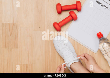 Ansicht von oben von Frau Hände Schuhe binden mit Sport Ausrüstungen auf Holz Hintergrund Stockfoto