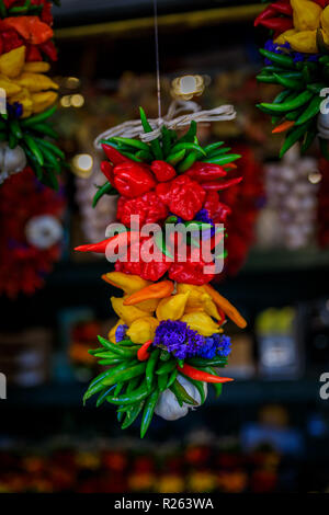Mehrfarbige Chili ristras, mit Blumen und Knoblauch eingerichtet, am Pike Place Market in Seattle hängen Stockfoto