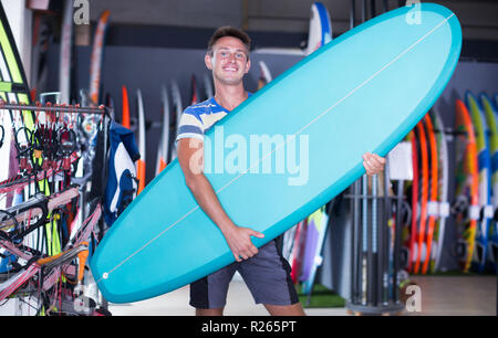 Portrait von erwachsenen Mann mit Surfbrett in nautischen Shop Stockfoto