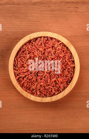 Roter Reis, Schuß von oben in eine hölzerne Schüssel auf einem dunklen rustikalen Hintergrund mit Kopie Raum Stockfoto