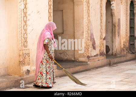 Alte Frau mit rosa Kopftuch in Sari sweeps Terrasse in Jodhpur Palace. Stockfoto