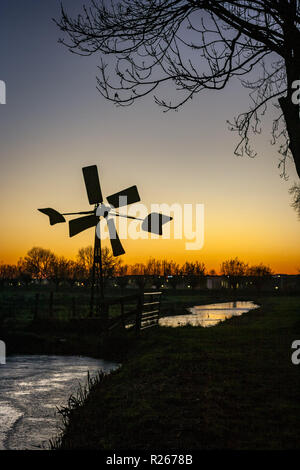 Silhouette einer Pumpen Mühle entlang einer niederländischen Canal gegen die Dämmerung Himmel. Der Himmel war an diesem Tag und Eis bereits begonnen, er zu Wasser. Stockfoto