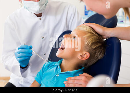 Zahnarzt in Weiß ist die Visional Inspektion eines Kindes auf dem Stuhl in der Klinik. Stockfoto