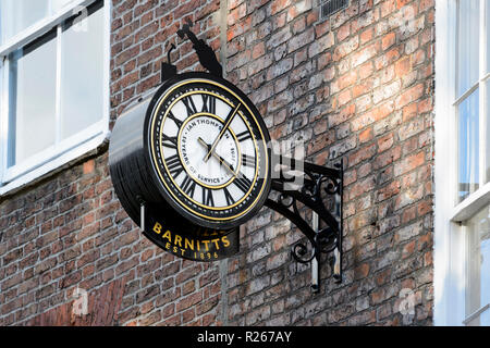 In der Nähe von öffentliche Uhr die Uhrzeit ablesen, montiert auf Mauer außerhalb Barnitt's Haus und Garten Shop - York, North Yorkshire, England, UK. Stockfoto