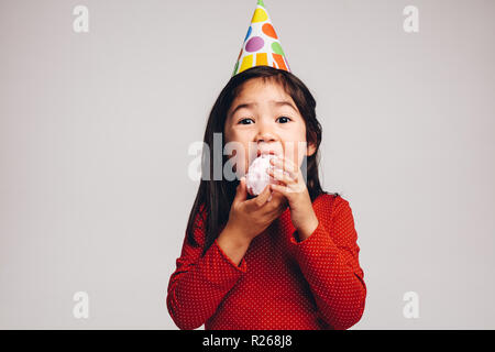 Kleines Mädchen mit einer Kappe auf dem Kopf essen Zucker Zuckerwatte. Nahaufnahme eines Kindes genießen Zuckerwatte. Stockfoto