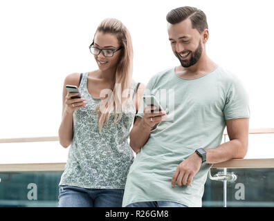 Junges Paar an die Bildschirme von ihren Smartphones suchen Stockfoto