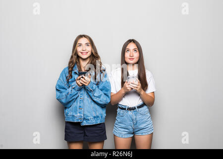 Porträt von zwei Mädchen soziales Netzwerk sucht auf Handys auf weißem Hintergrund Stockfoto