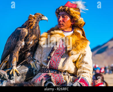 ULGII, Mongolei - OKTOBER 6, 2018: Golden Eagle Festival. Der goldene Adler Jäger zu Pferd mit Blick auf die gut ausgebildeten Adler auf seiner Hand an der c Stockfoto