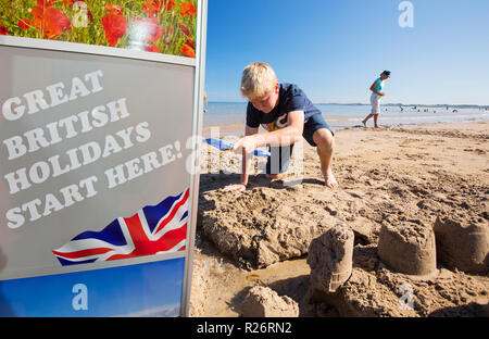 Ein Junge, bauen eine Sandburg am Strand von Bamburgh, Northumberland, UK. Stockfoto