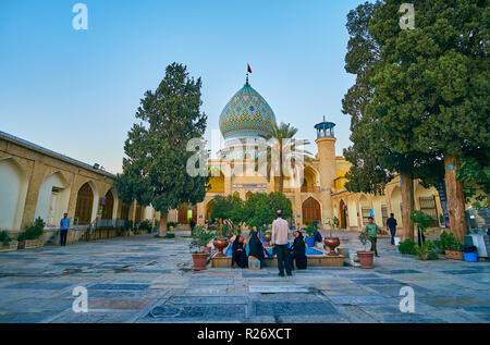 SHIRAZ, IRAN - Oktober 12, 2017: Die Besucher des Imamzadeh Ali Ibn Hamzeh heiligen Schrein an den malerischen Garten im Innenhof gelegen, am 12. Oktober Stockfoto